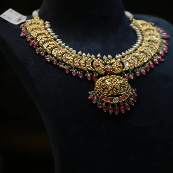 Polki and ruby necklace set with matching earrings on a dark bust